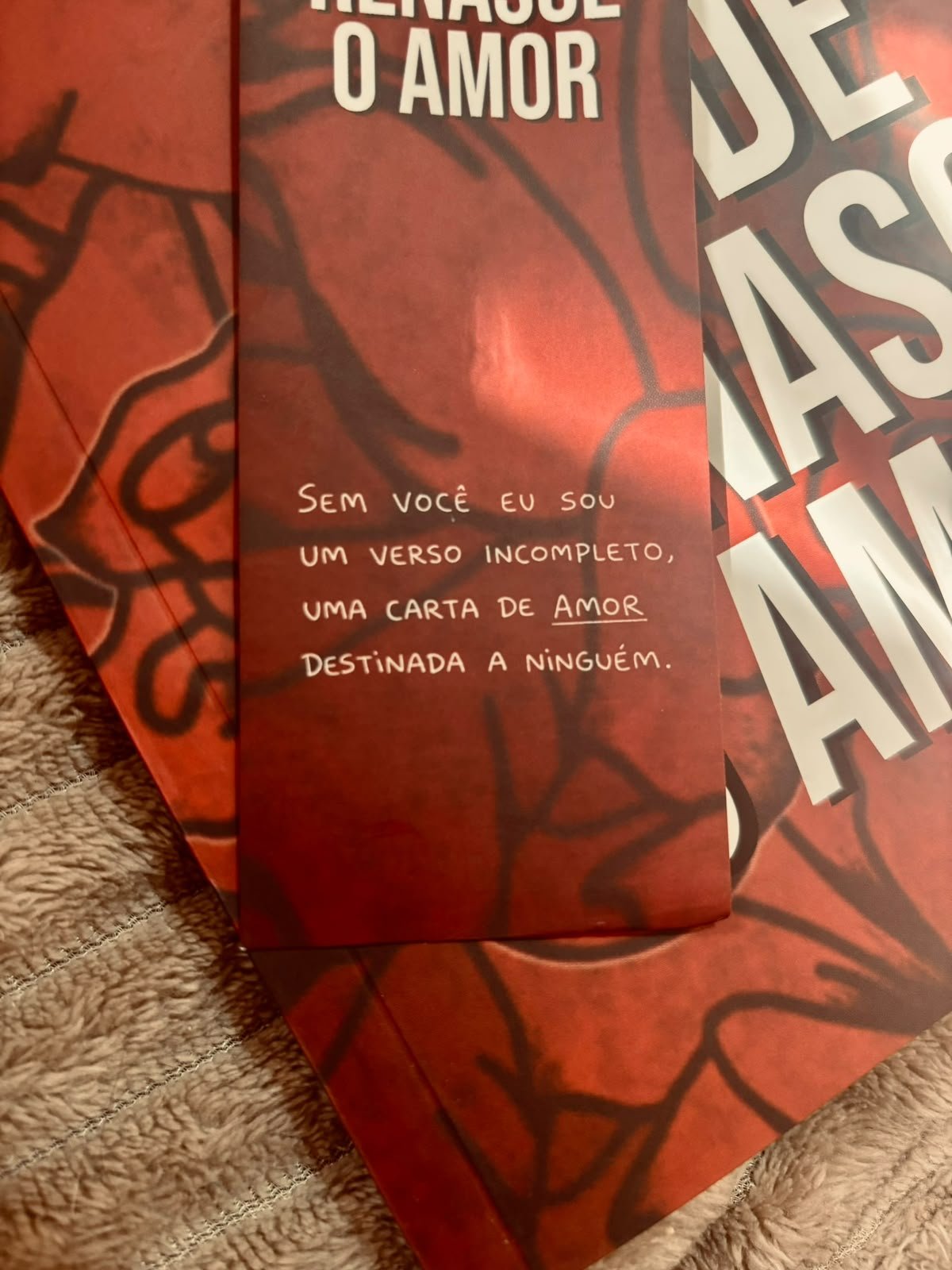Livros com capas em tons de vermelho sobre tecido bege texturizado.