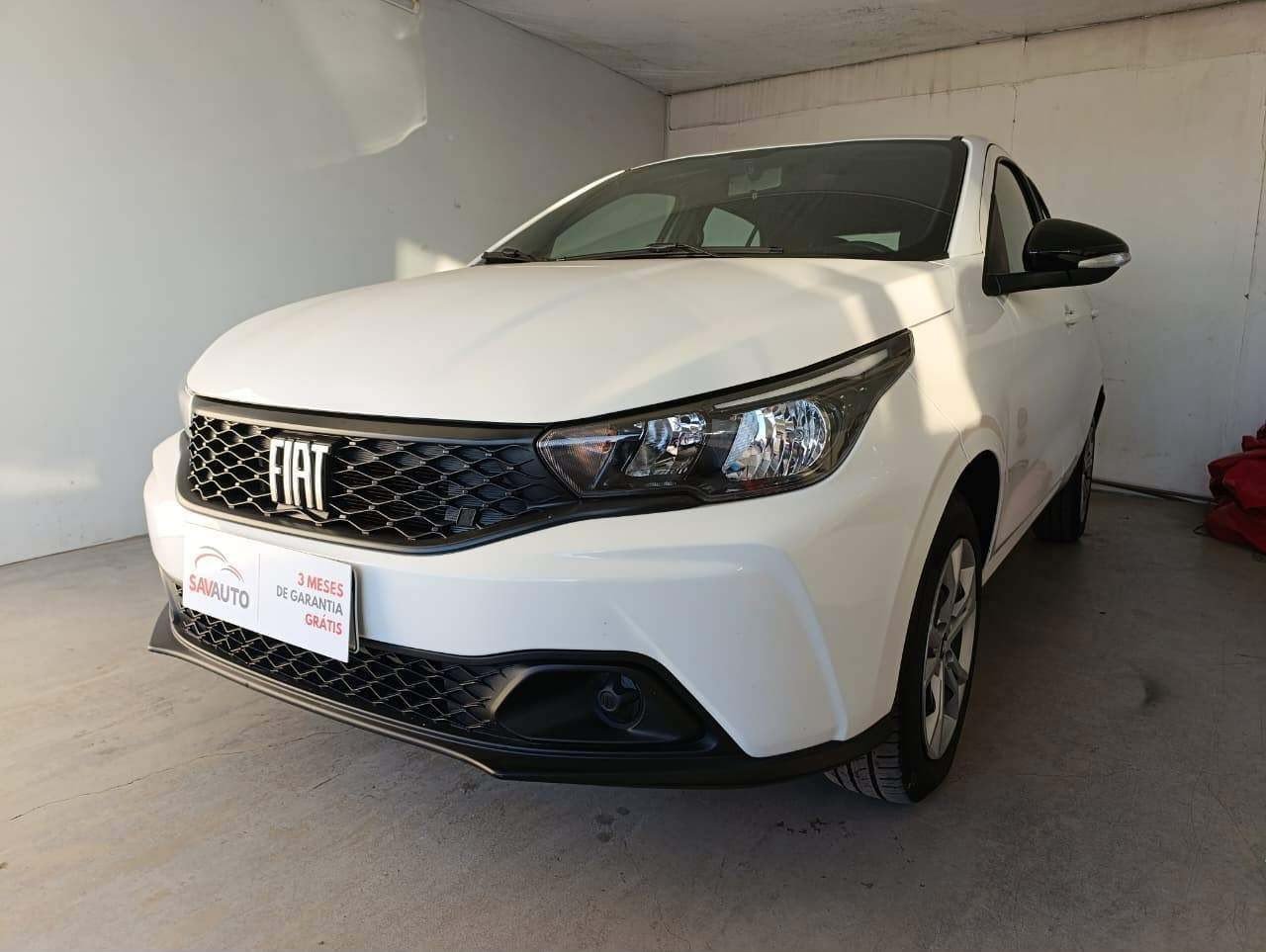 Automóvel branco fotografado de frente e pela lateral em ambiente interno