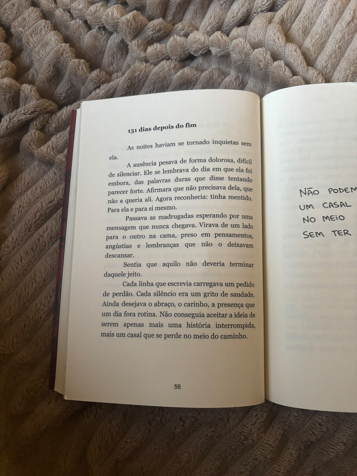 Livro aberto sobre uma manta felpuda, com texto impresso e trechos manuscritos parcialmente visíveis.